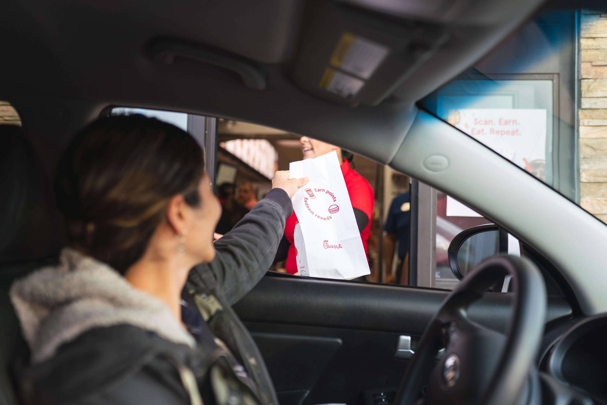 A person grabbing fast food through a drive-through window